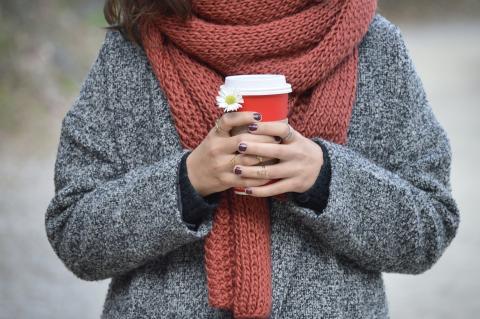 person wearing scarf while holding cup